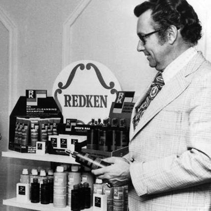 Man in black and white holding Redken product.